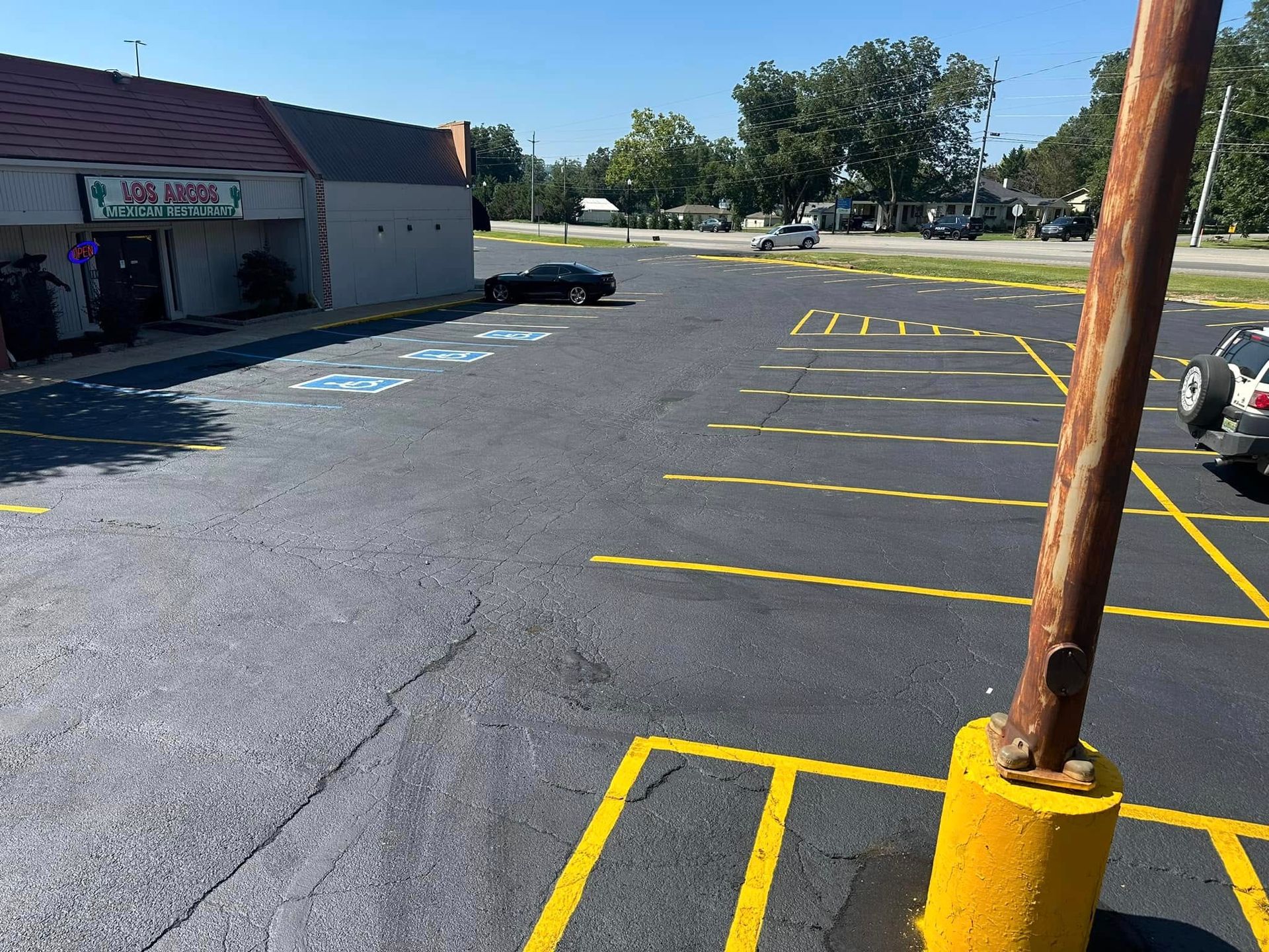 Exterior of parking lot with a few cars parked near a building and utility pole.