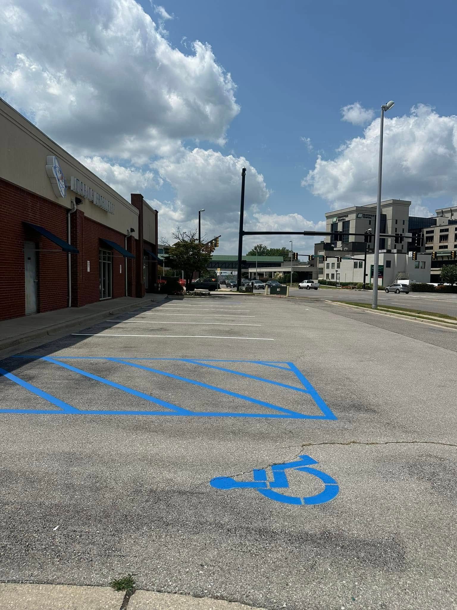 Parking lot with a blue handicap symbol and painted lines; sunny day.