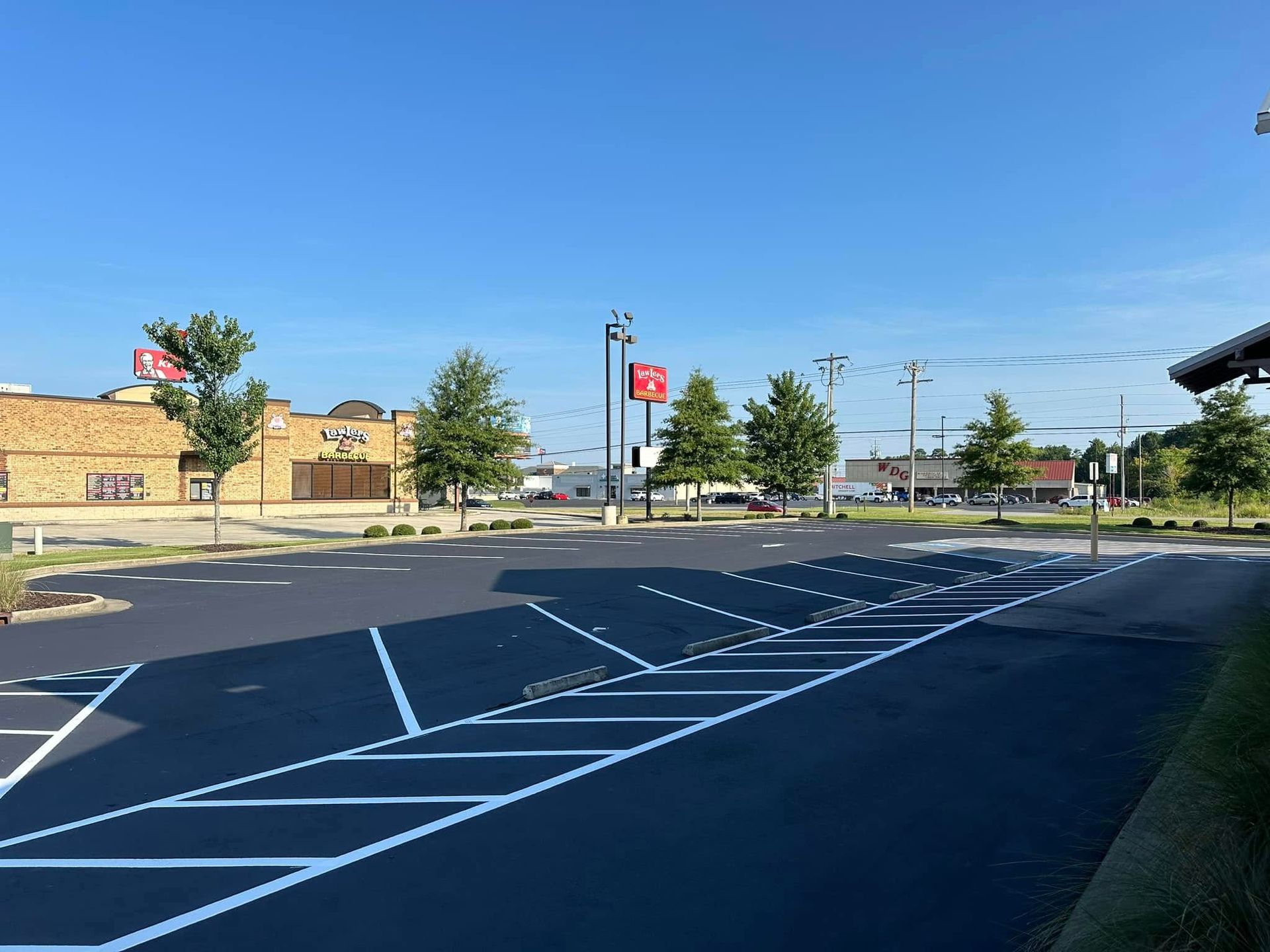 Empty parking lot with freshly painted white lines. Buildings and blue sky in the background.