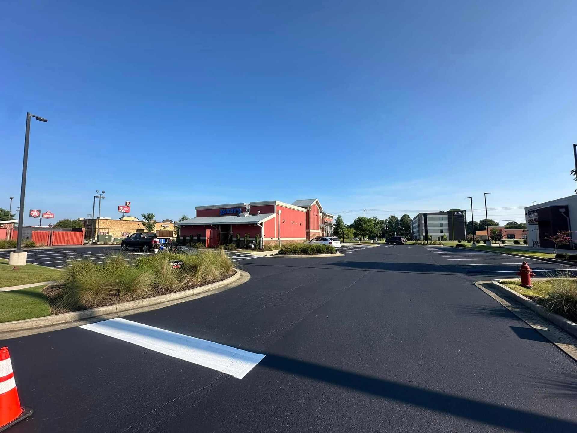 Paved road leading to a red building with solar panels. Clear blue sky overhead.