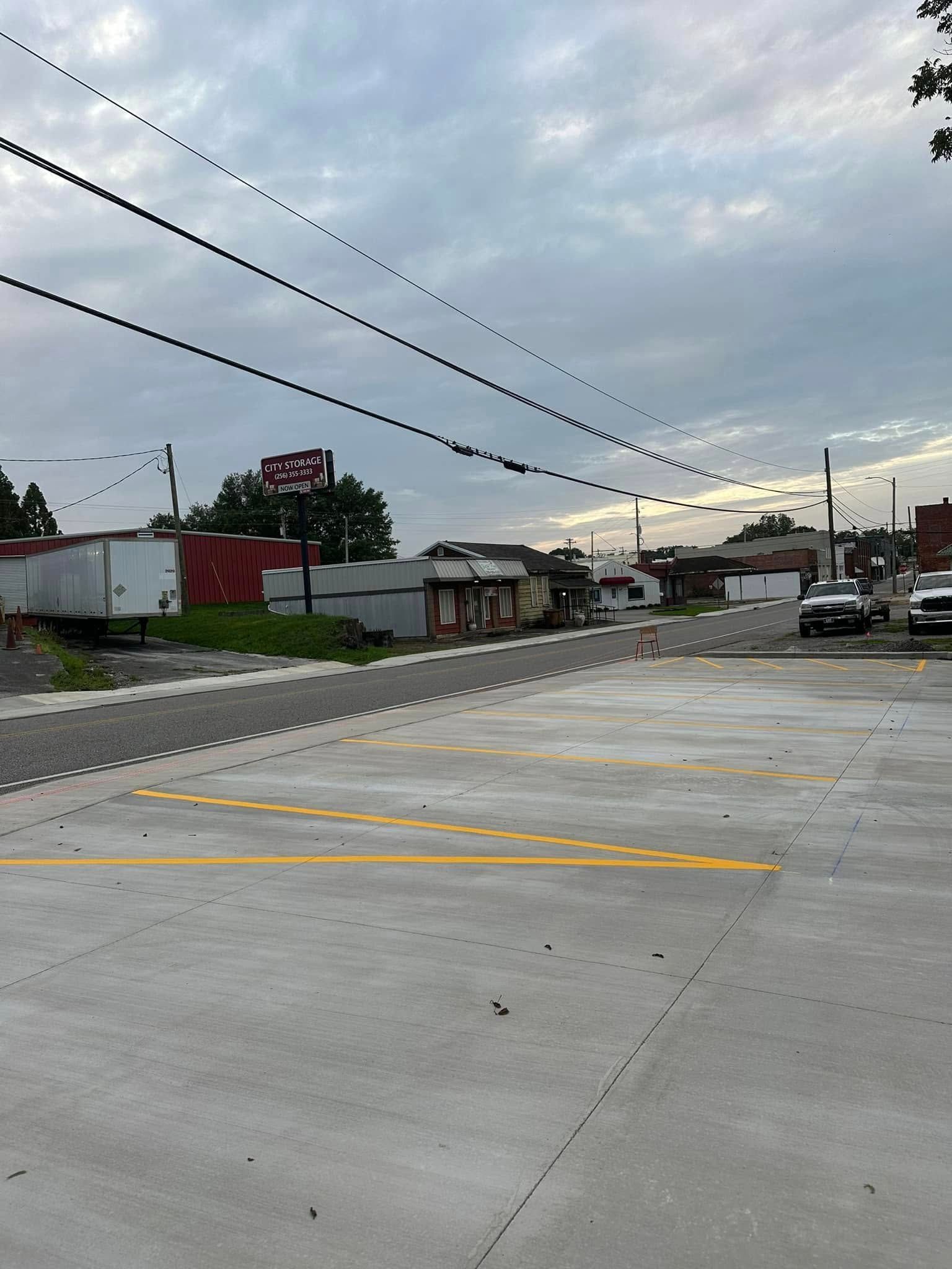 Exterior view of a parking lot and buildings under a cloudy sky. Power lines are visible overhead.