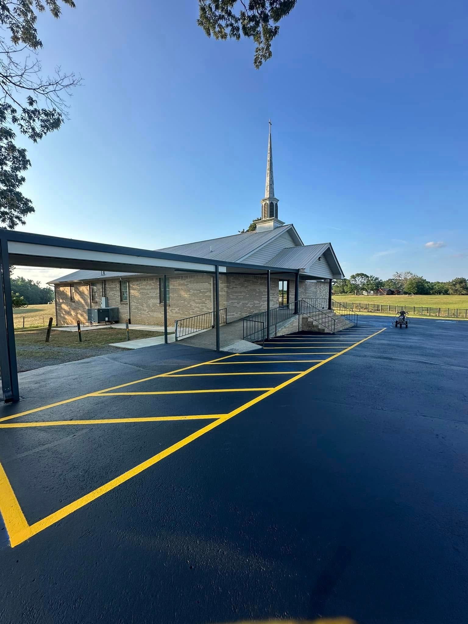 Temple building with a tall spire and parking lot, blue sky.