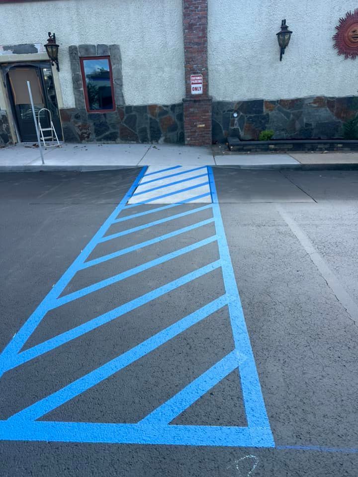 Blue striped handicapped parking space on asphalt next to a building.