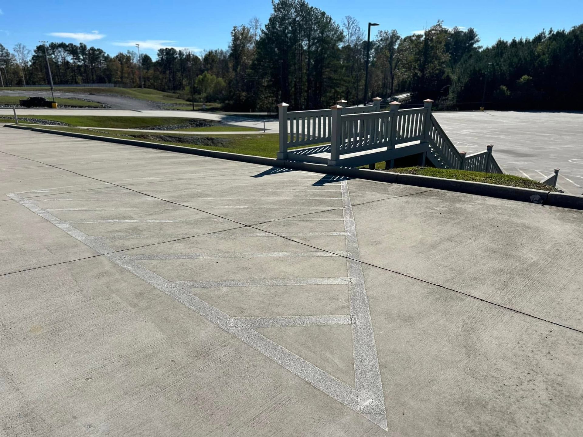 Concrete parking lot with a painted triangular shape and wooden bridge.