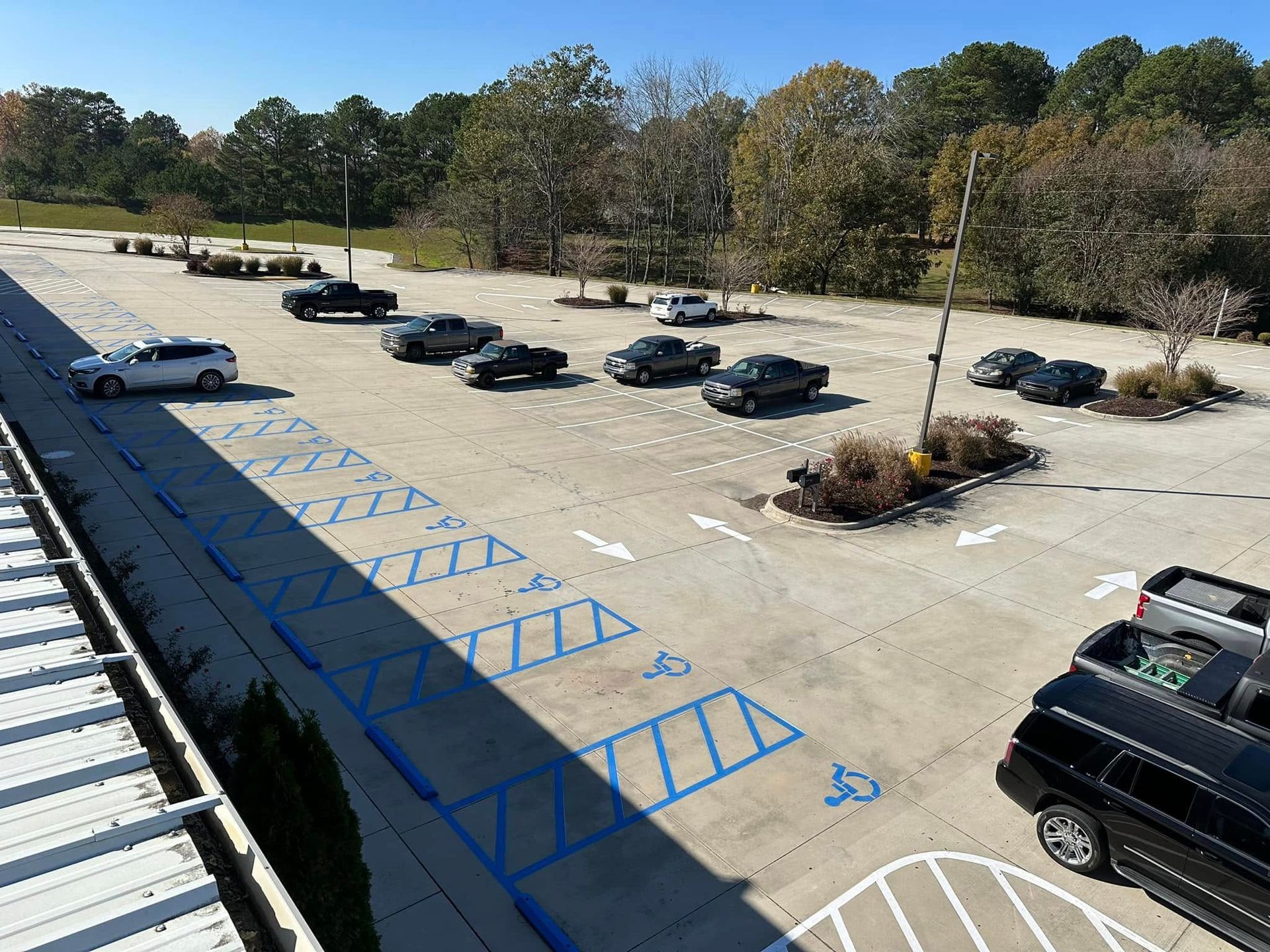 Parking lot with marked spaces, some with accessibility symbols. Several vehicles parked.