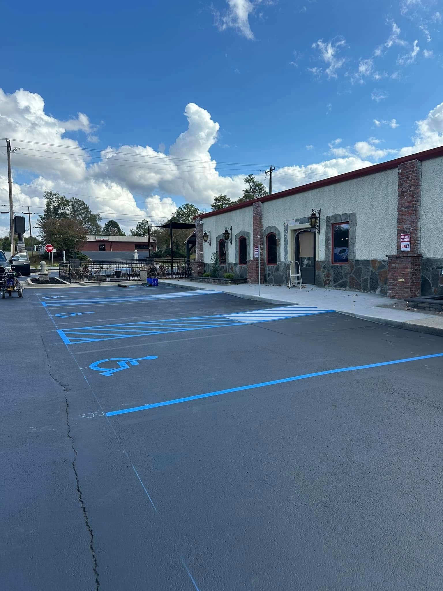 Exterior view of a building with blue handicapped parking spaces painted on the asphalt parking lot.