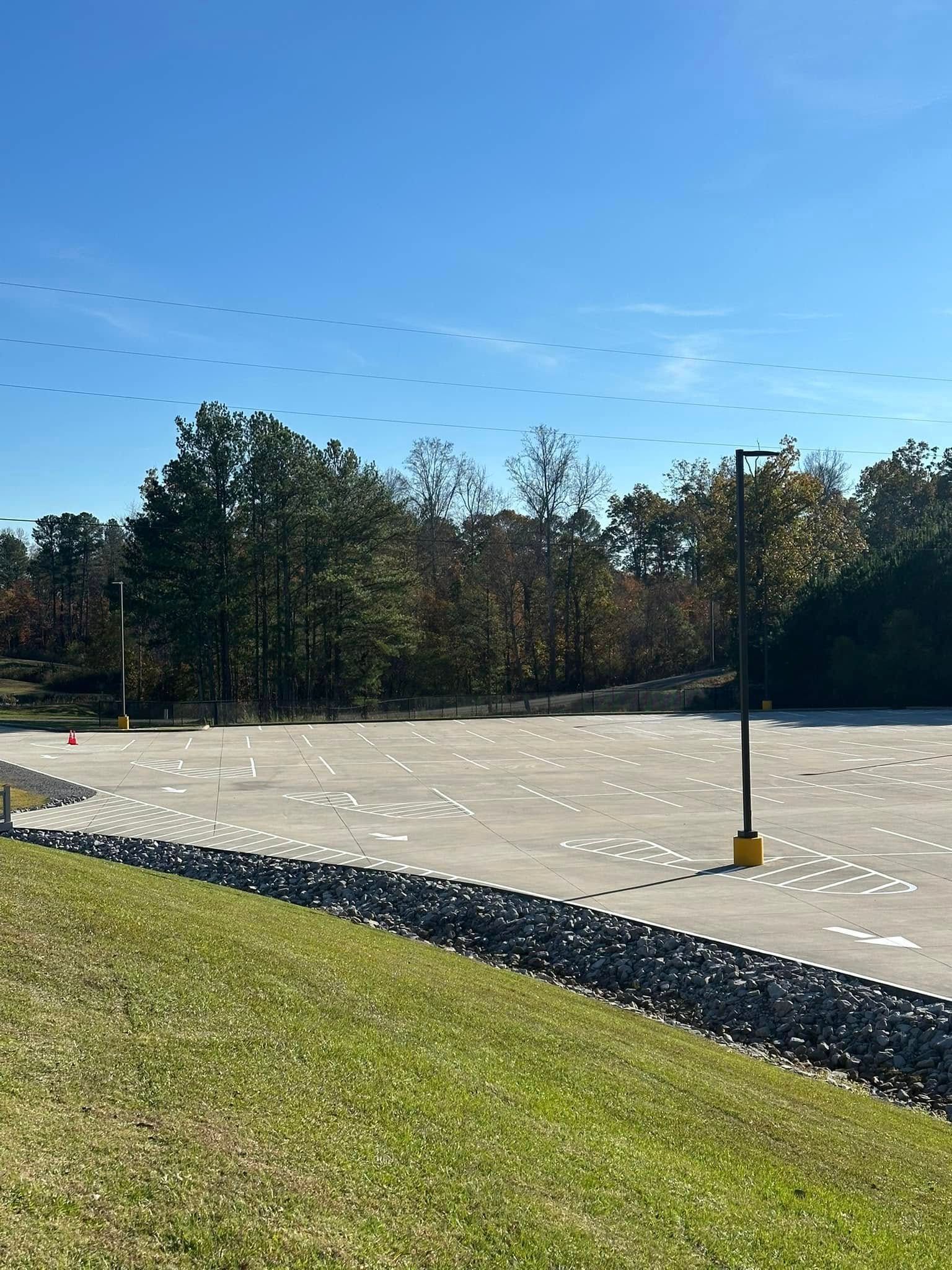 Grassy foreground, paved area marked with white lines, trees in background, and a blue sky.