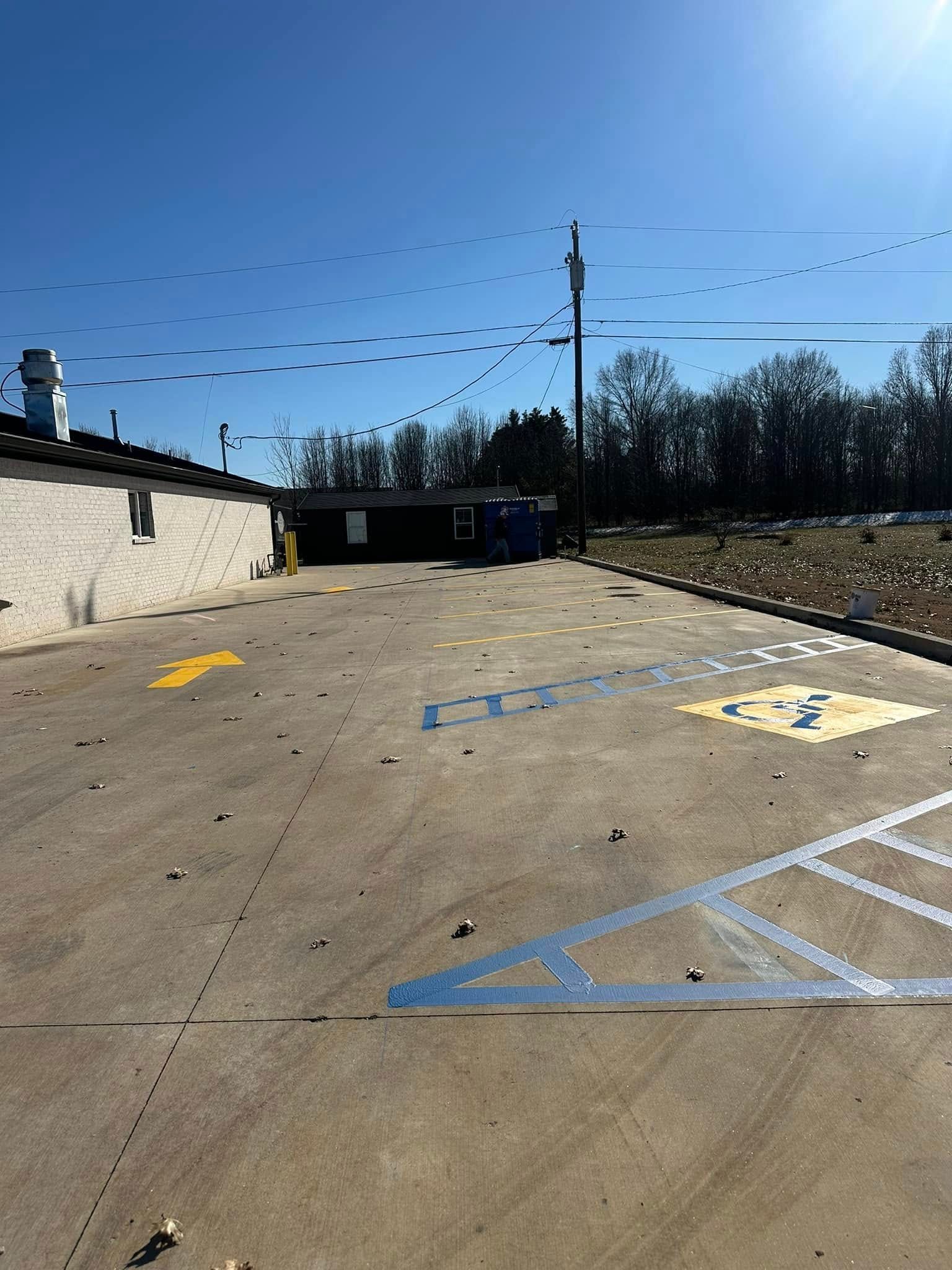 Exterior view of a commercial building with a parking lot. Blue and yellow parking space markings on concrete. 