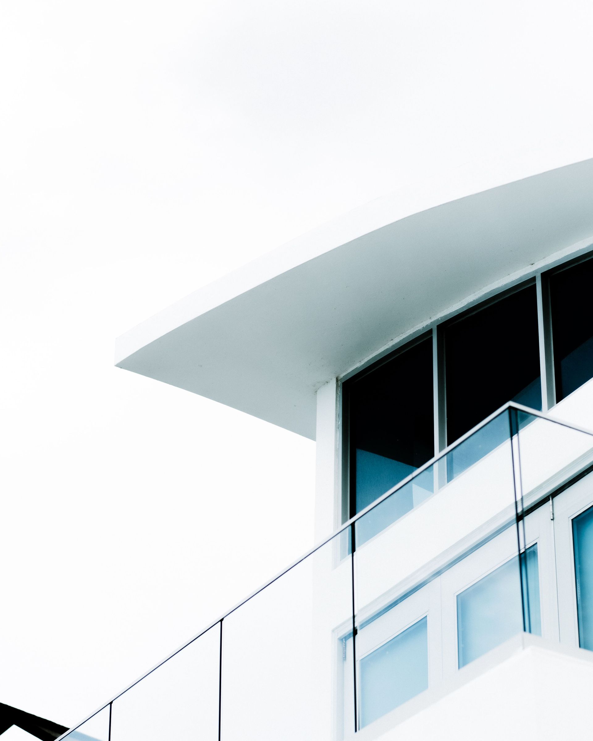 Modern building corner with a curved white roof and blue-tinted windows against a bright sky
