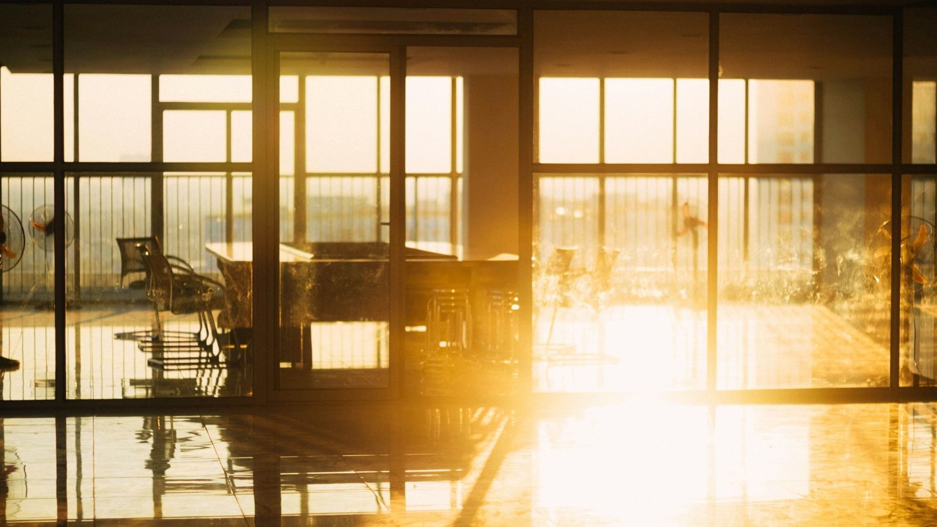 Sunlit modern room with glass walls and reflections at sunset