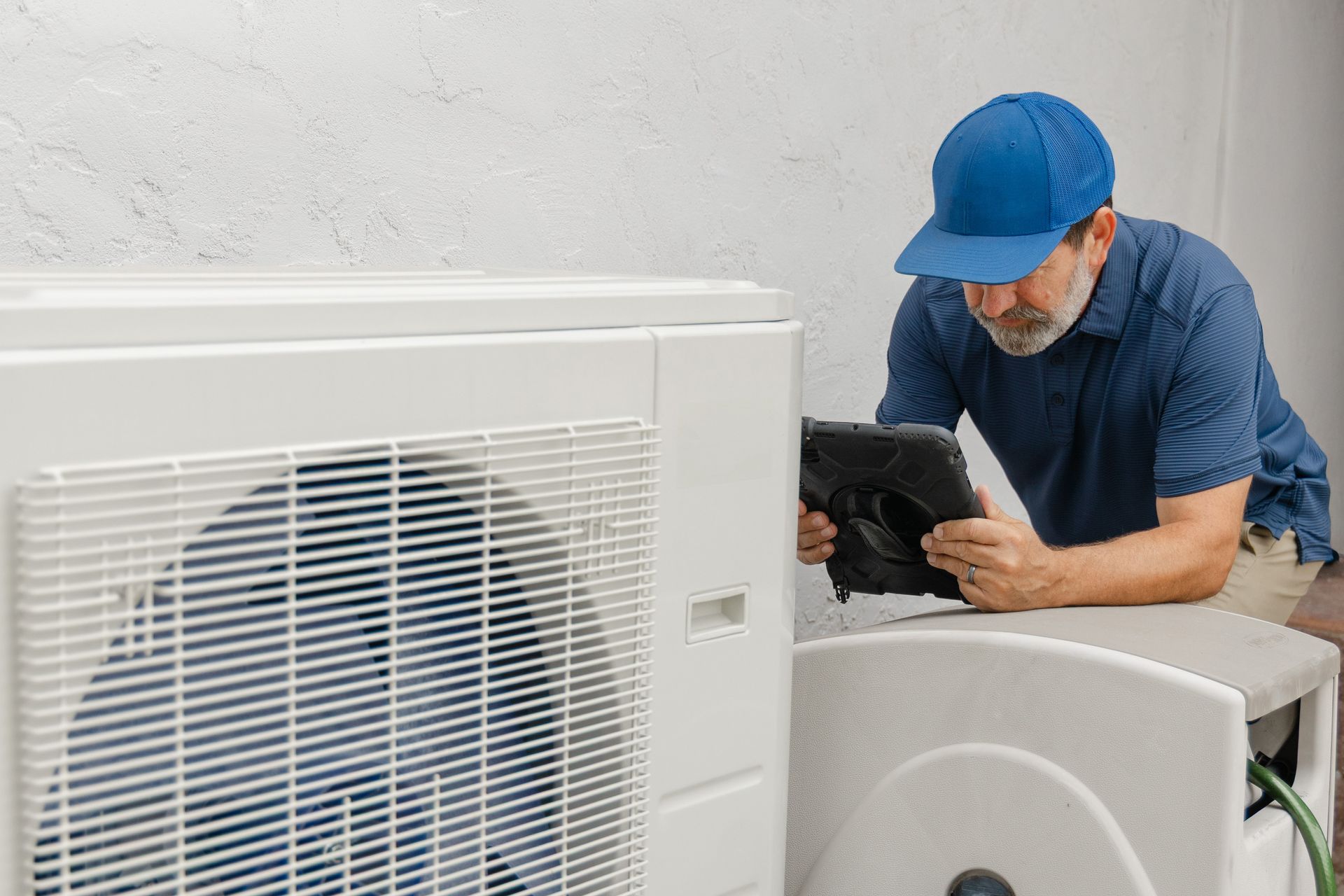 A professional technician is inspecting heating and cooling system at a residential home. A professional technician is inspecting heating and cooling system at a residential home.
