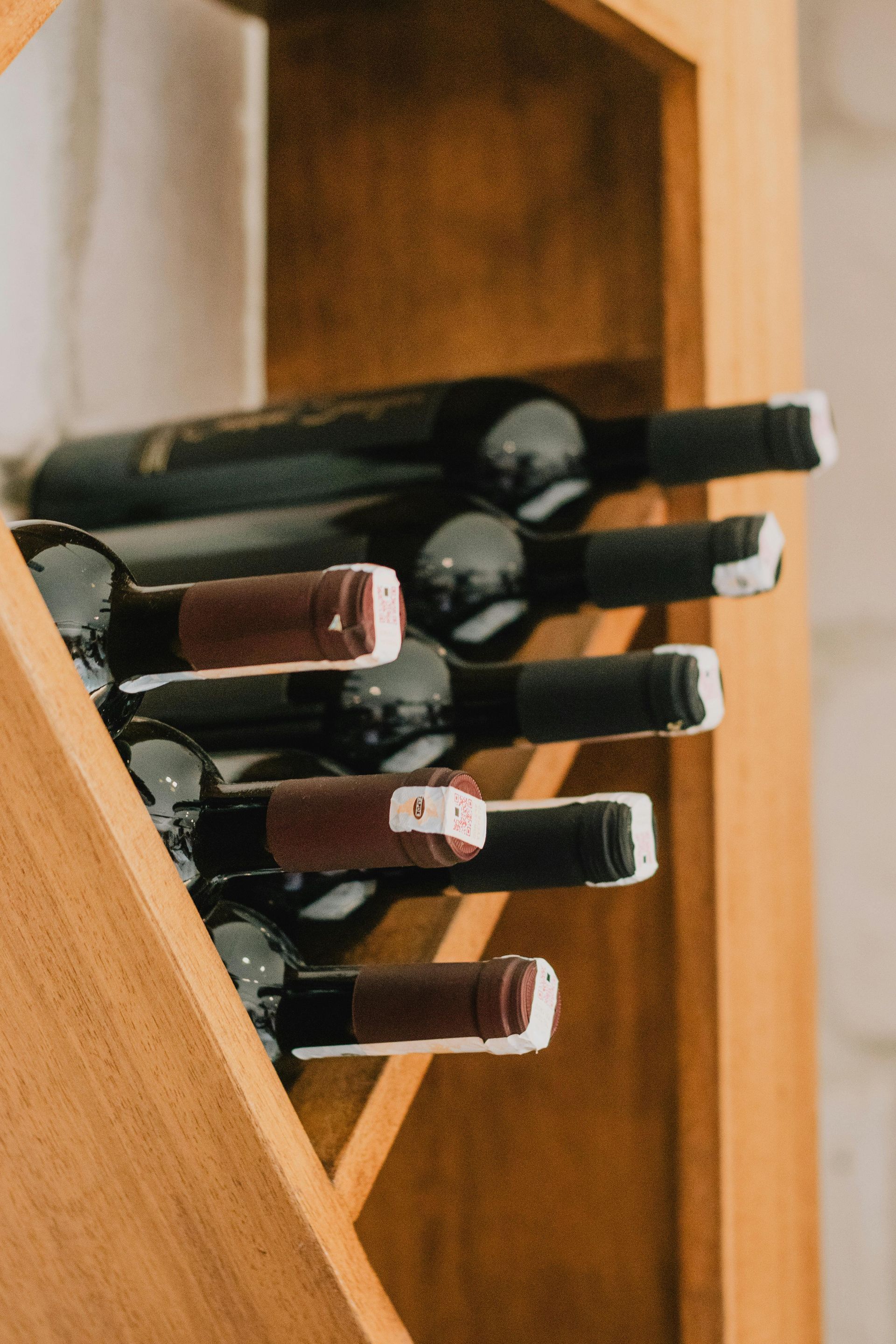 A row of wine bottles sitting on top of a wooden shelf.