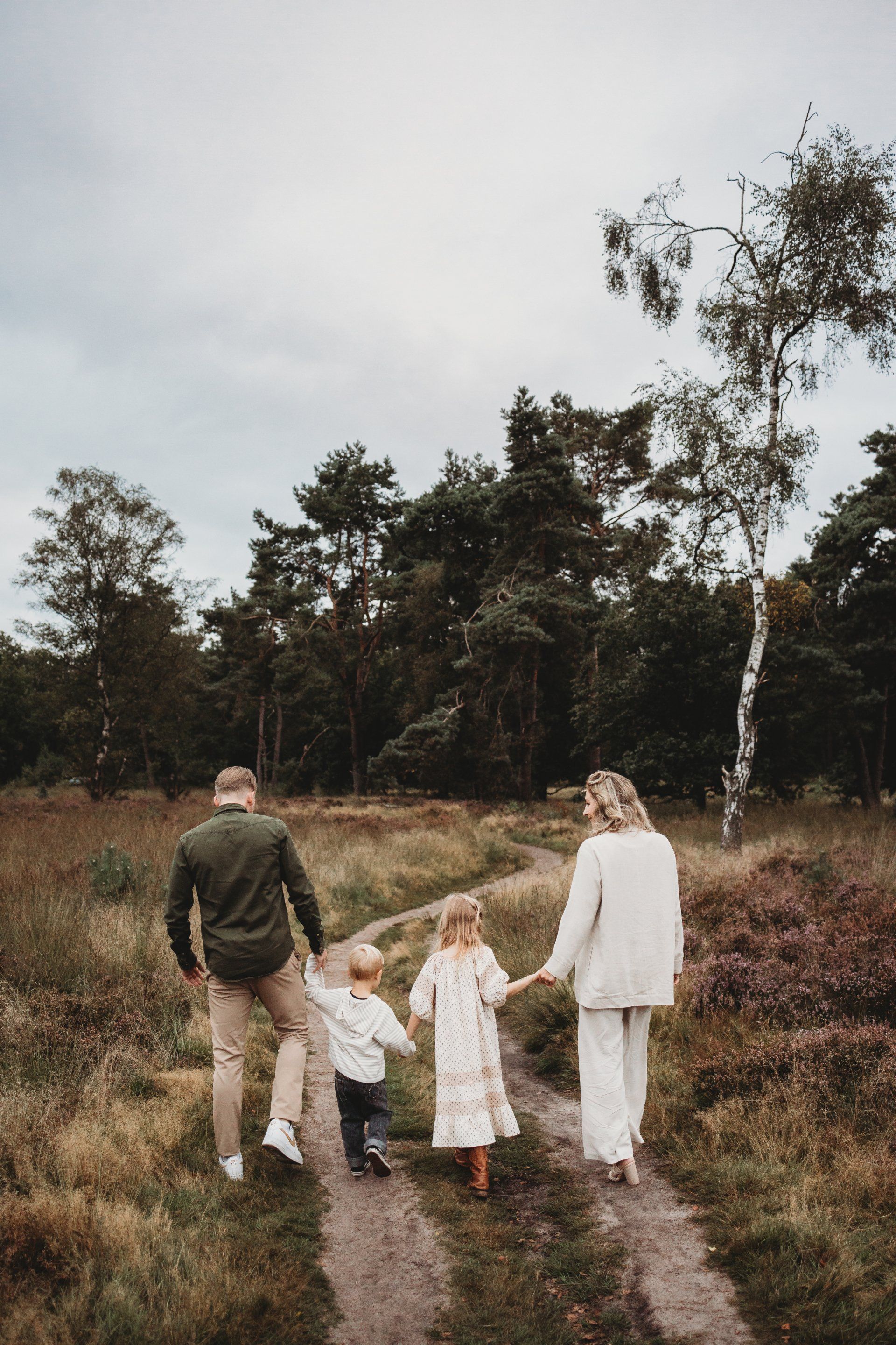 Een gezin loopt hand in hand over een zandpad in Den Treek tijdens familieshoot.