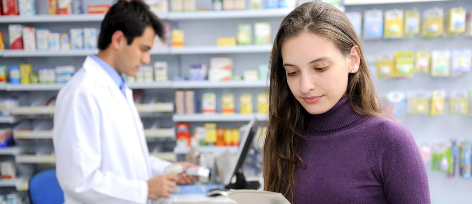 Una mujer está parada frente a un farmacéutico en una farmacia.