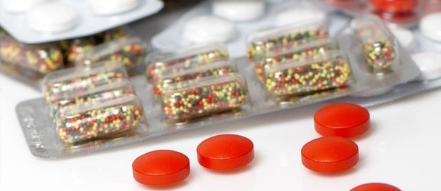 Un blíster de pastillas rojas y blancas sobre una mesa.