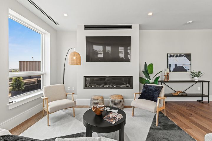 Bright modern living room with fireplace, large windows, and two armchairs around a small round table