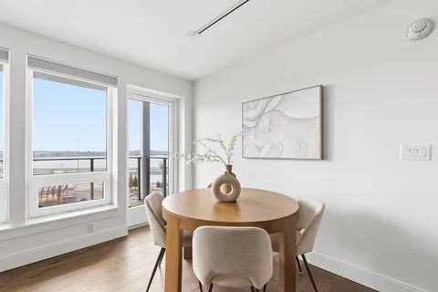 Bright dining nook with round wooden table, two chairs, and large windows overlooking water