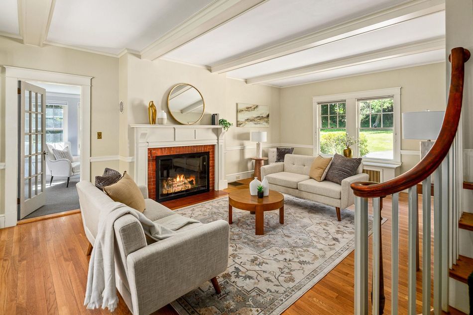 Bright living room with white fireplace, gray sofas, wood floors, and large windows