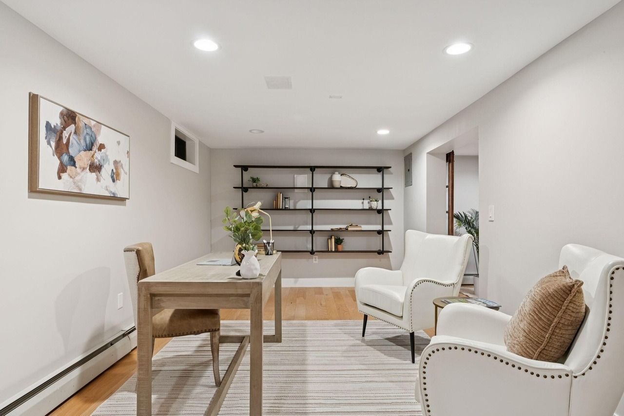 Bright minimalist living room with beige chairs, wood table, shelves, and soft neutral decor