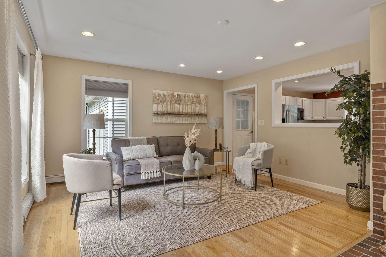 Bright living room with white chairs, gray sofa, rug, wall art, and hardwood floors