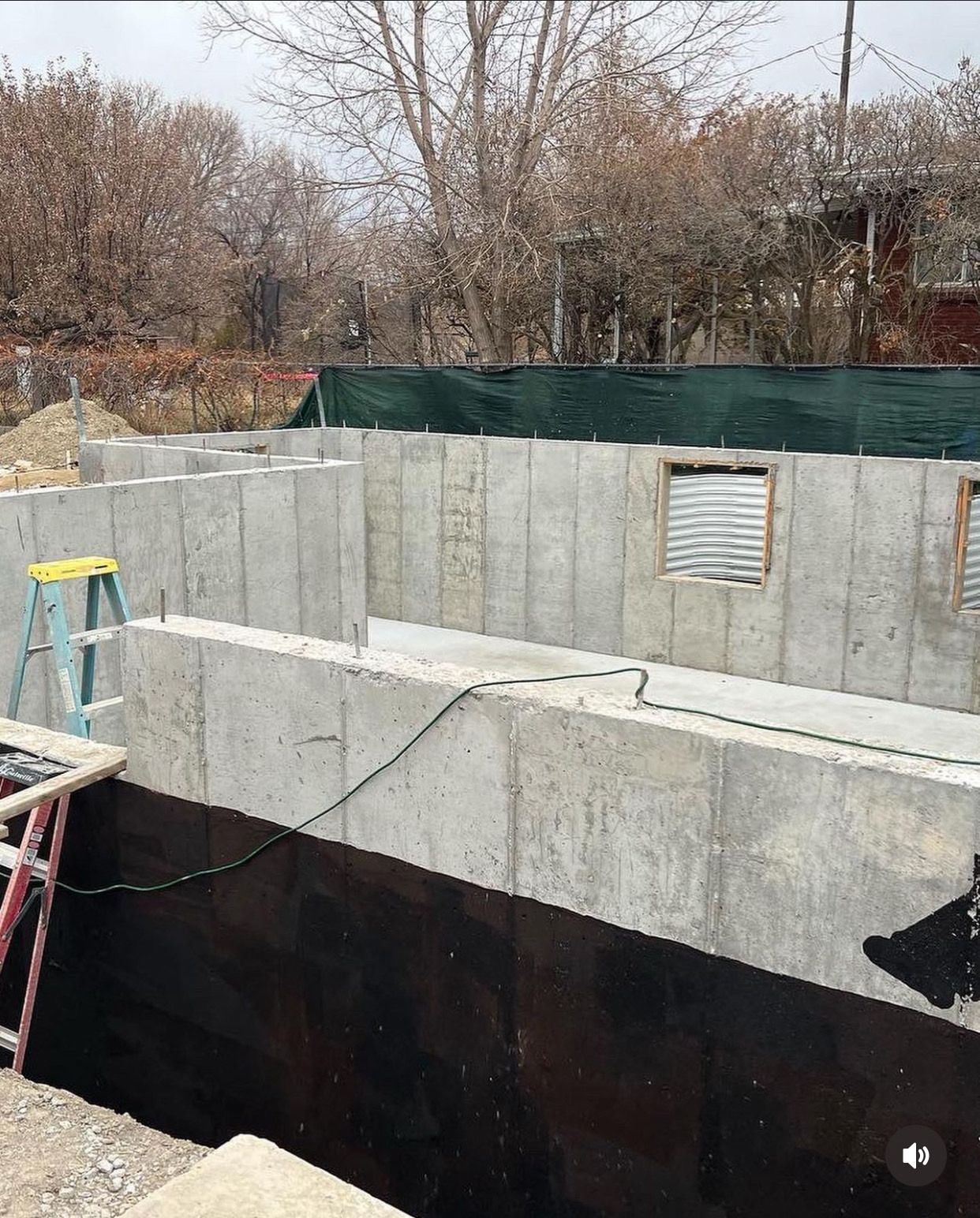 A ladder is sitting on top of a concrete wall.