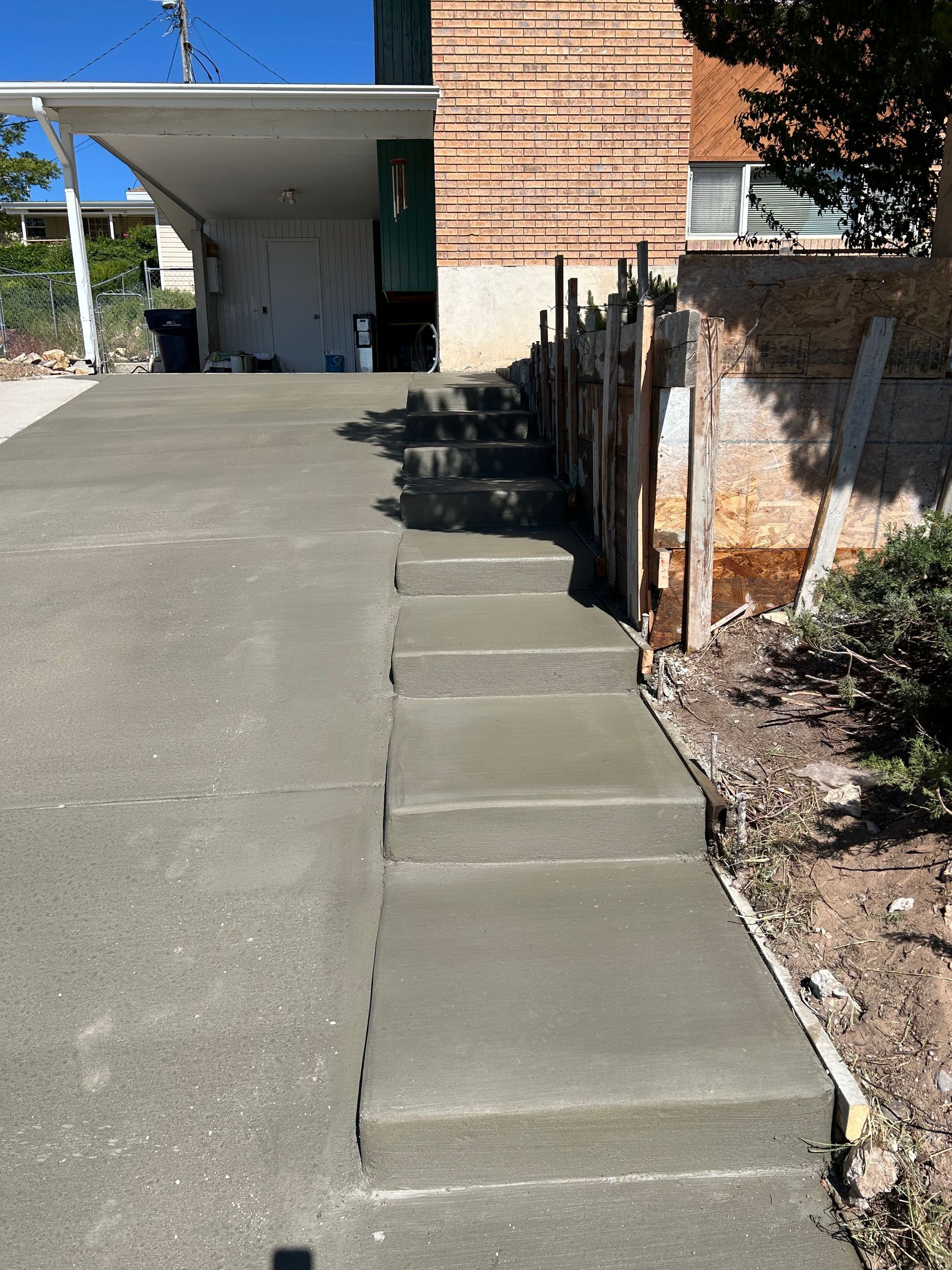 Concrete ramp with steps beside a brick building and driveway