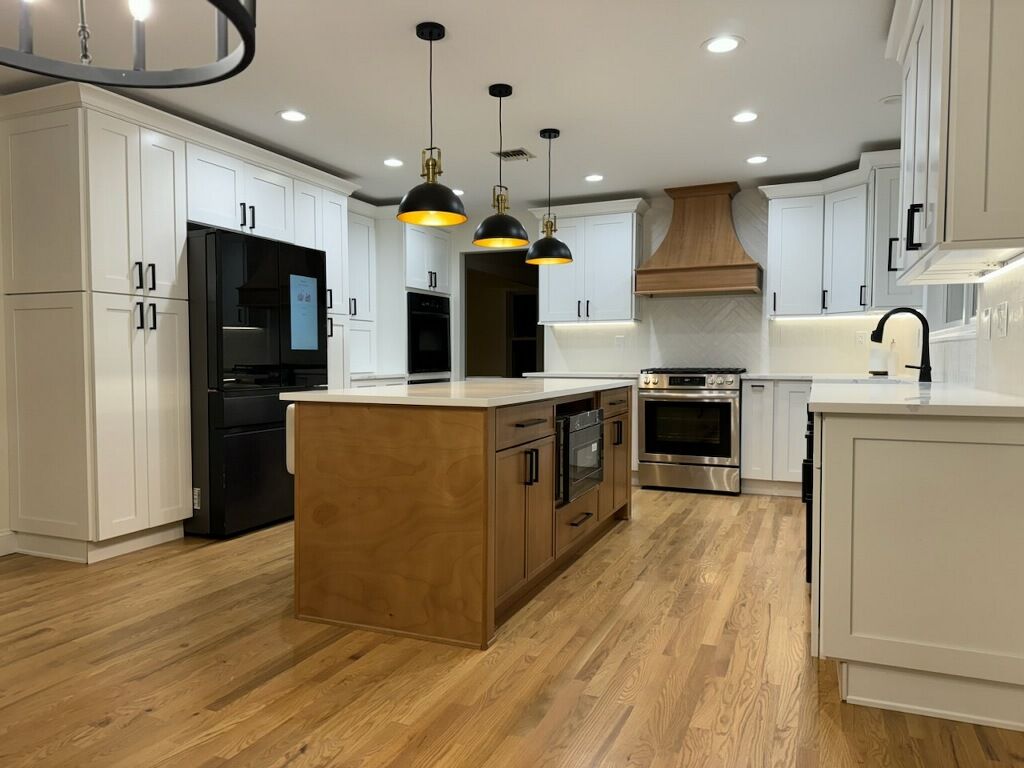 Bright modern kitchen with white cabinets, wood island, black appliances, and pendant lights.