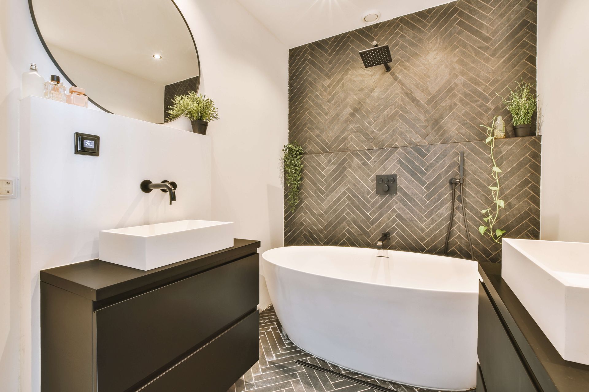 Modern bathroom with freestanding tub, black vanity, and herringbone tile accent wall