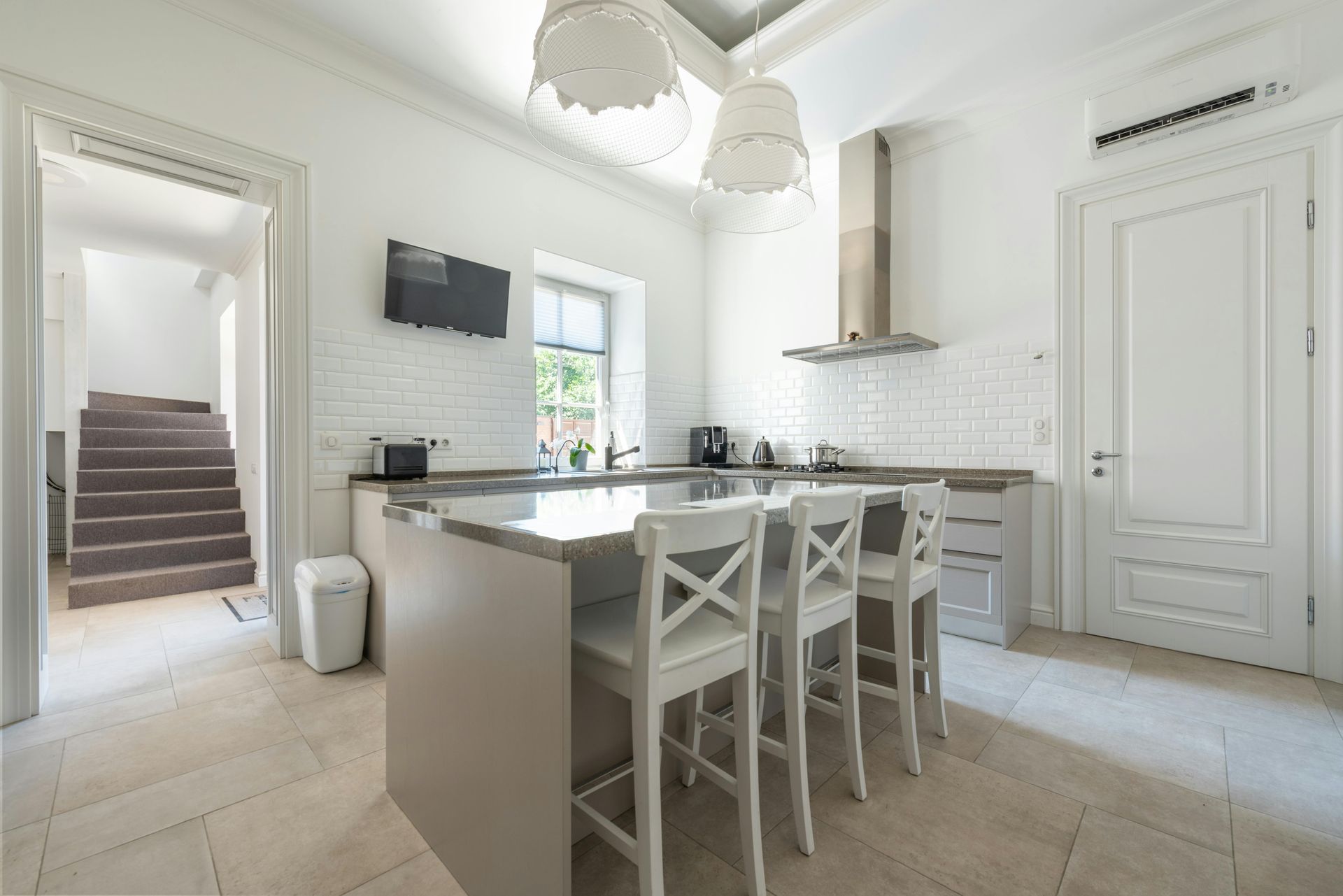 Bright modern kitchen with white cabinets, island seating, and marble tile floor