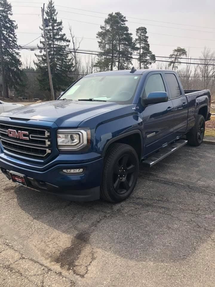 A blue gmc sierra pickup truck is parked in a parking lot