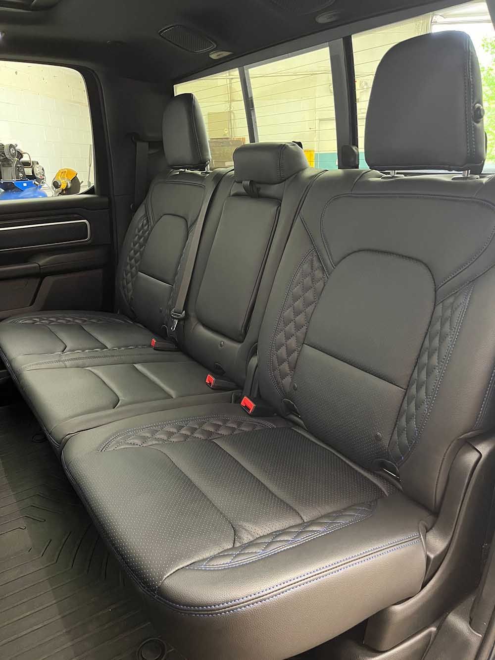 The back seat of a ram truck with black leather seat covers