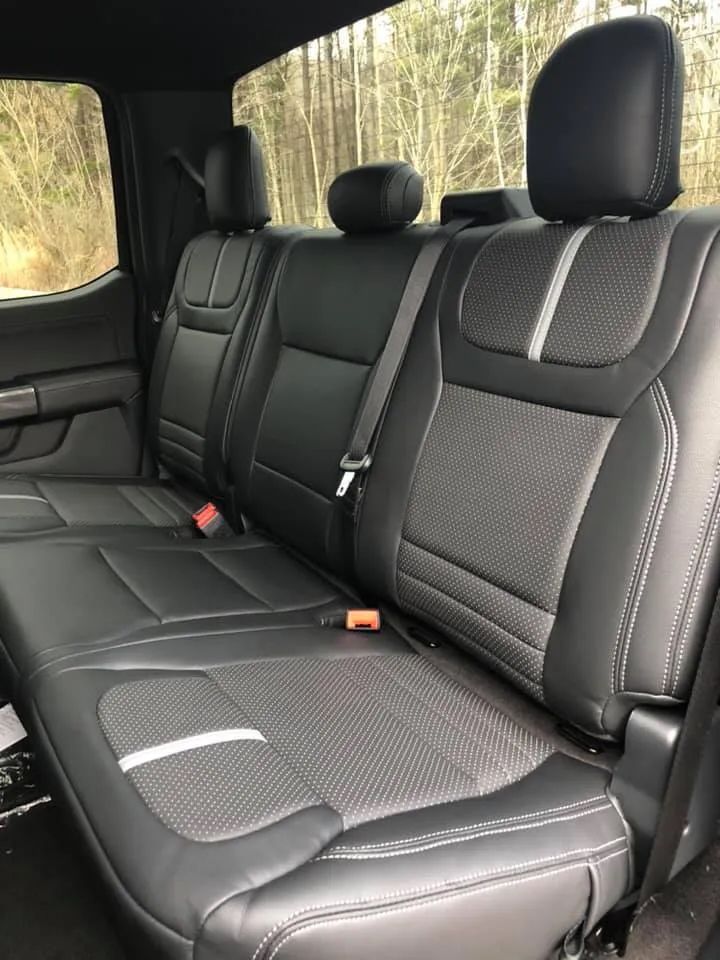 The back seat of a truck with black seat covers