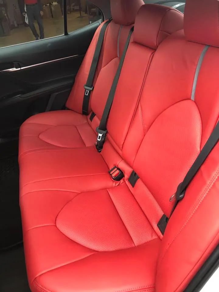The back seat of a car with red seats and black seat belts