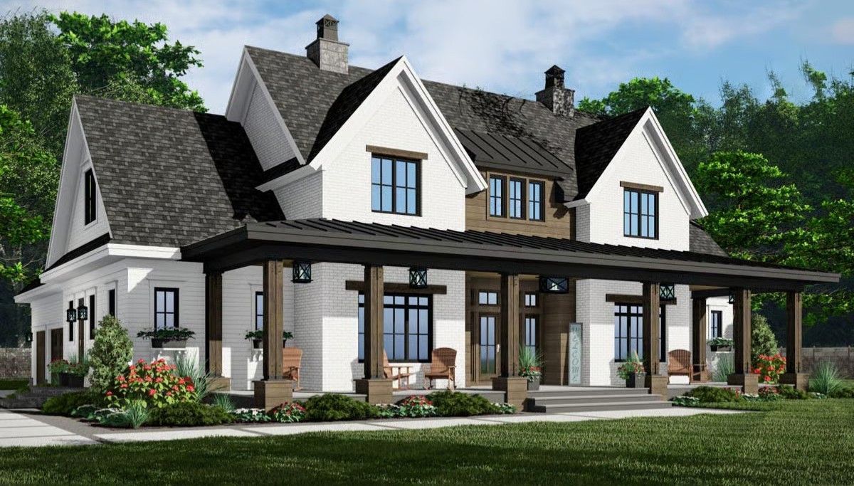 Large white house with dark roof, porch columns, and landscaped front yard under a blue sky