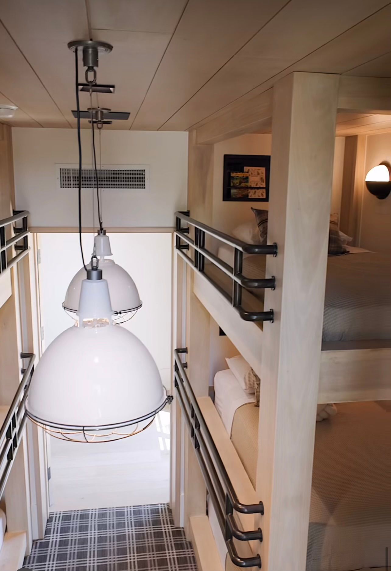 Modern interior atrium with hanging white pendant lights and metal railings on upper walkways