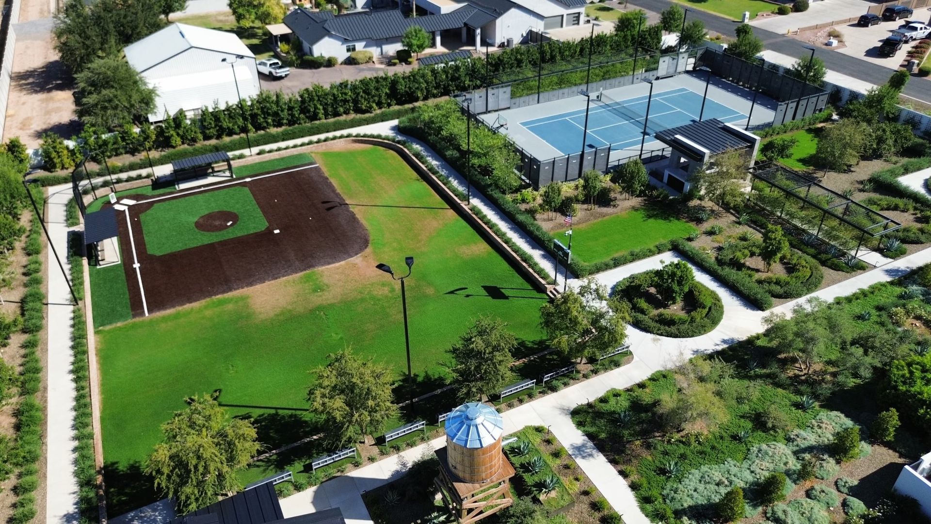 Aerial view of a baseball field beside tennis courts, walking paths, and green park grounds