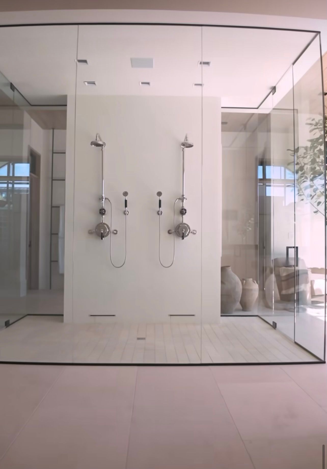 Modern glass-enclosed shower with dual chrome fixtures and a minimalist white interior.