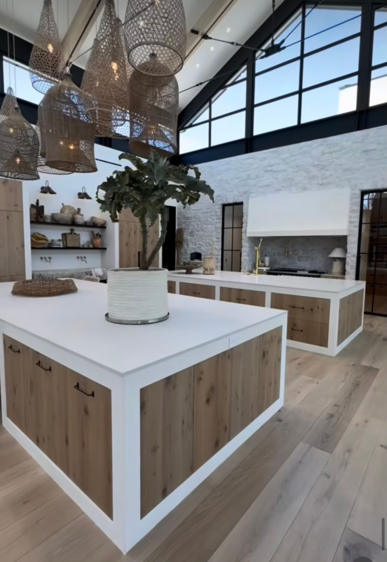 Modern kitchen with white island, wood accents, woven pendant lights, and large windows