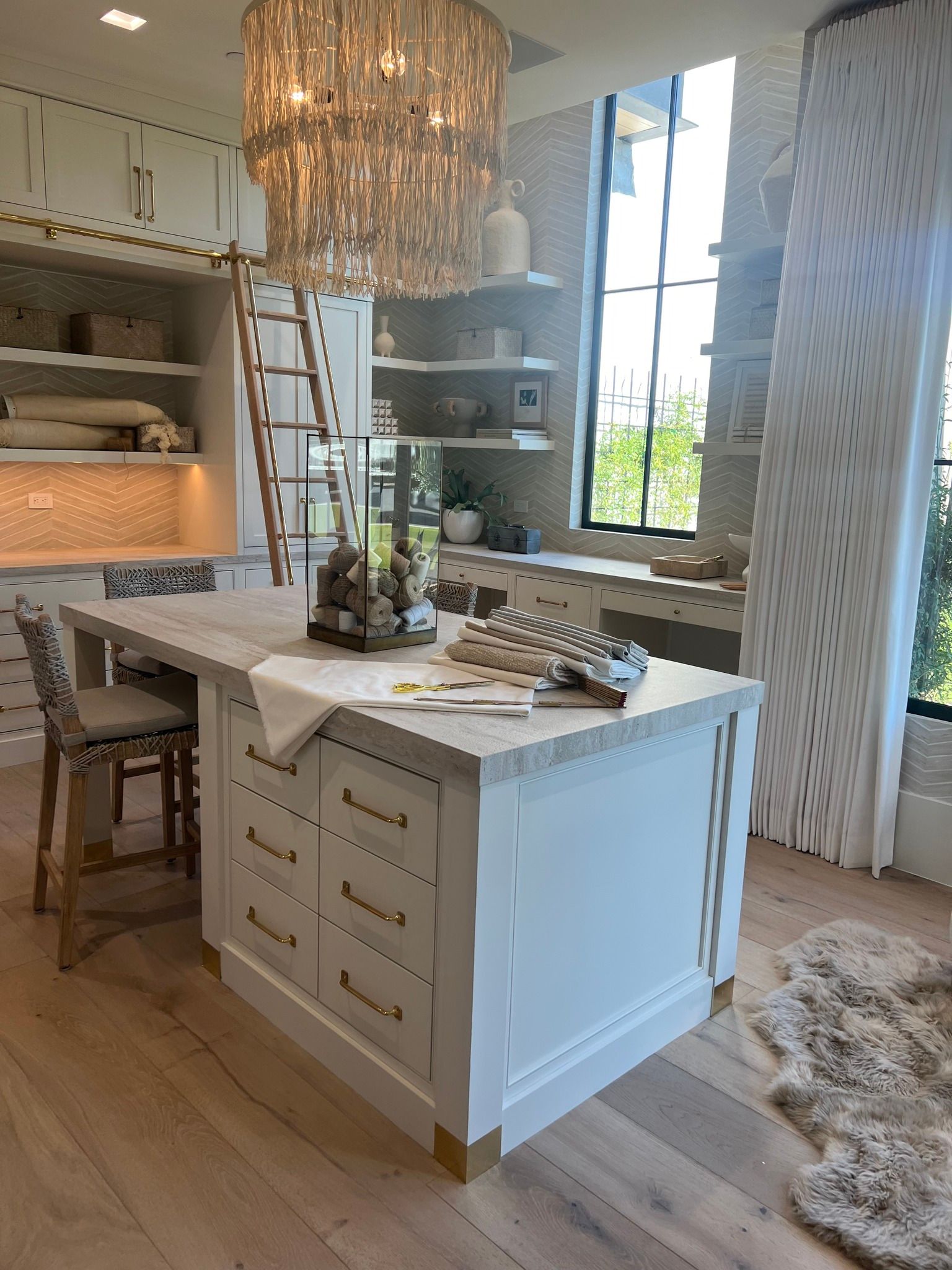 Bright white kitchen island with table setting, chandelier, and large window in a sunlit room
