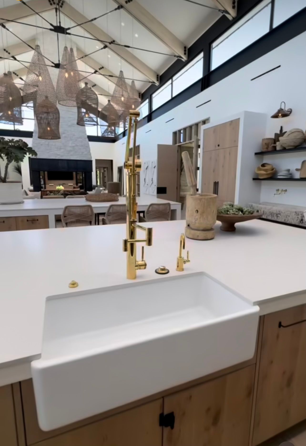 Modern kitchen with white island, brass faucet, wood cabinetry, and high vaulted ceiling