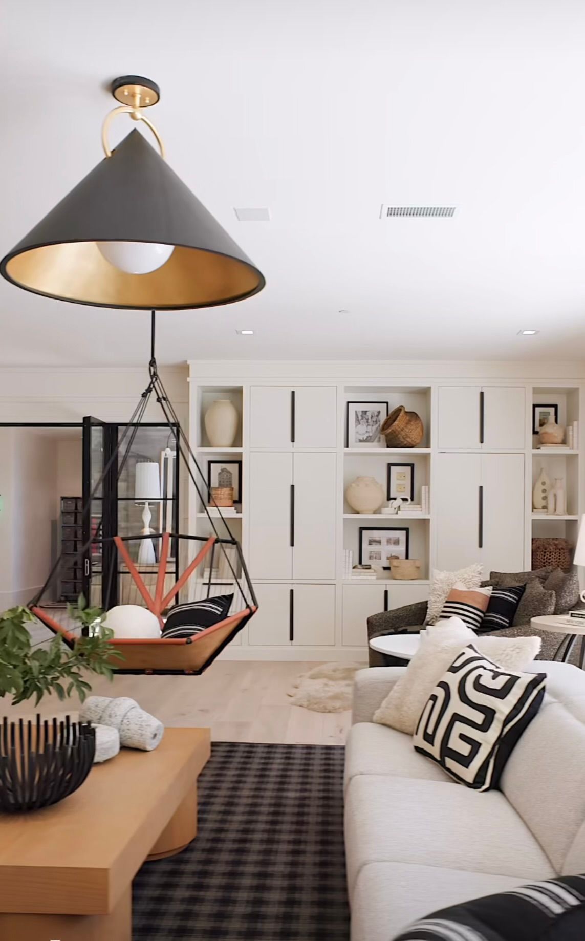 Modern living room with hanging chair, built-in shelves, white sofa, and black-and-white decor