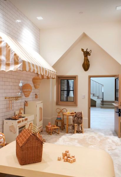Cozy pastel playroom with a dollhouse, toy kitchen, woven basket, and deer wall decor