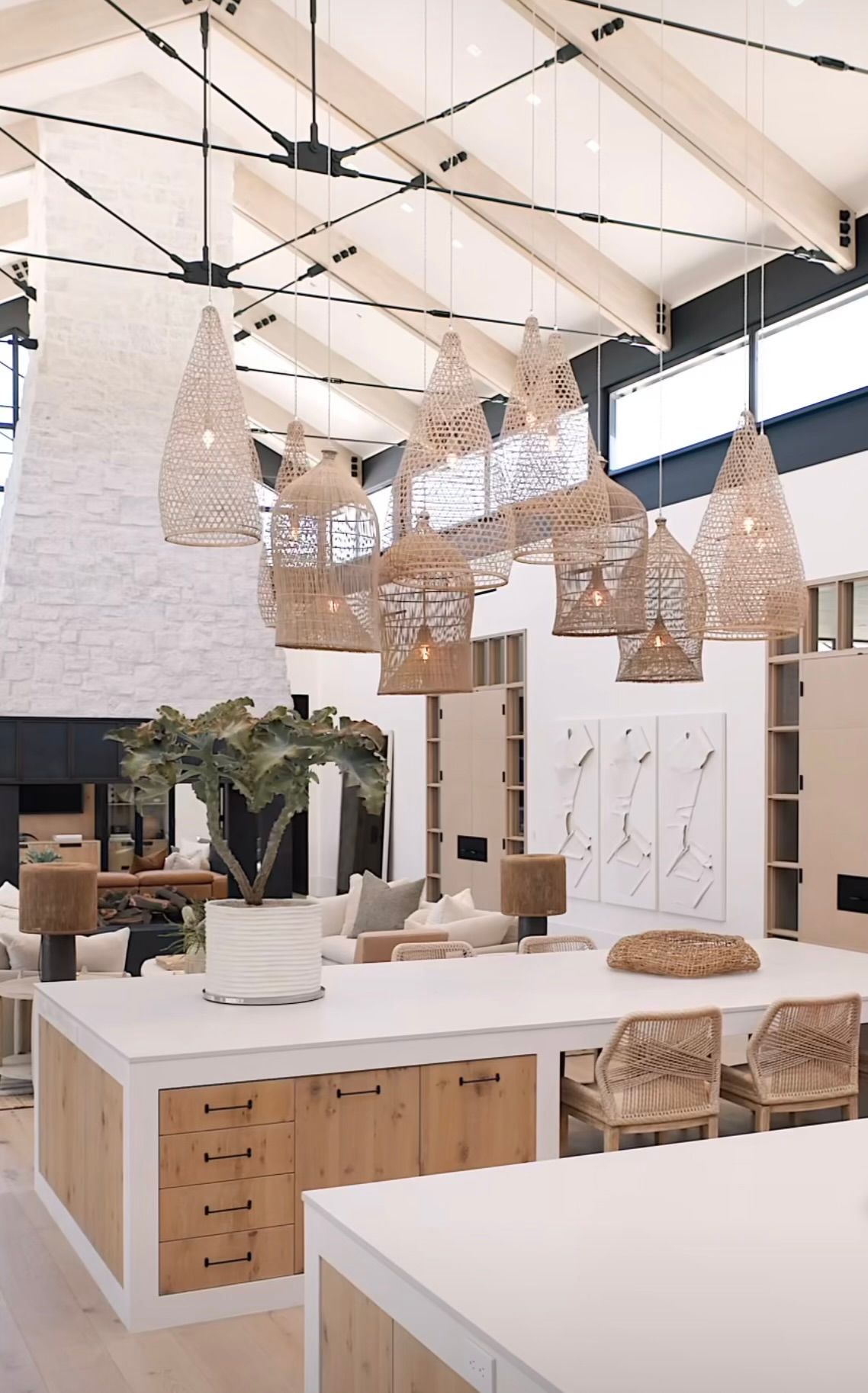 Bright, modern kitchen showroom with white island, woven pendant lights, and high ceilings