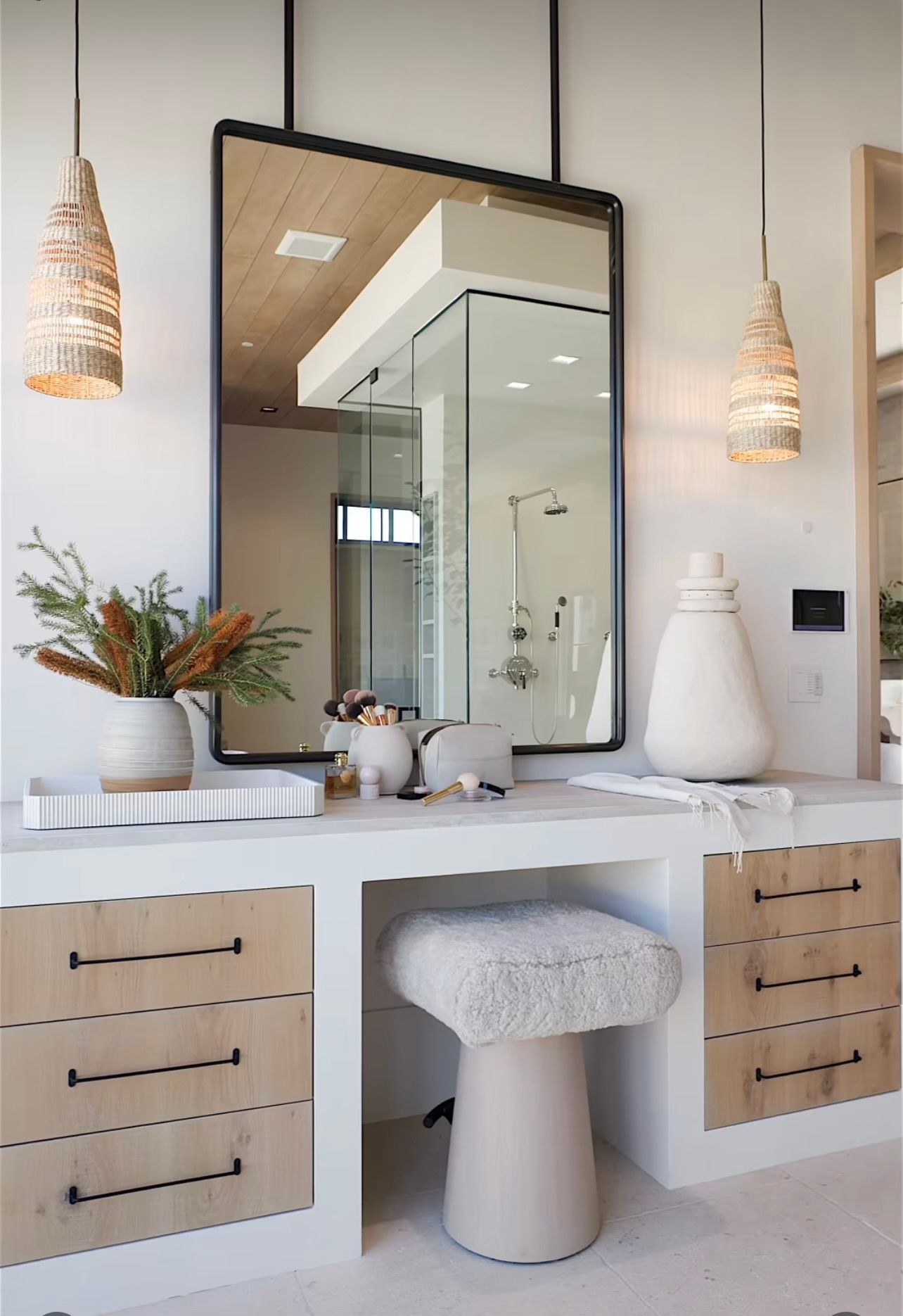 Modern vanity with large mirror, white countertop, and matching stool in a bright bathroom.