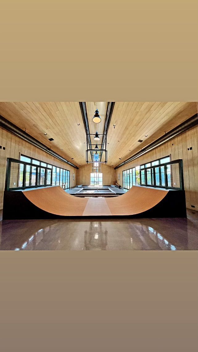 Long, empty train car interior with tan walls, windows, overhead lights, and a glossy floor.