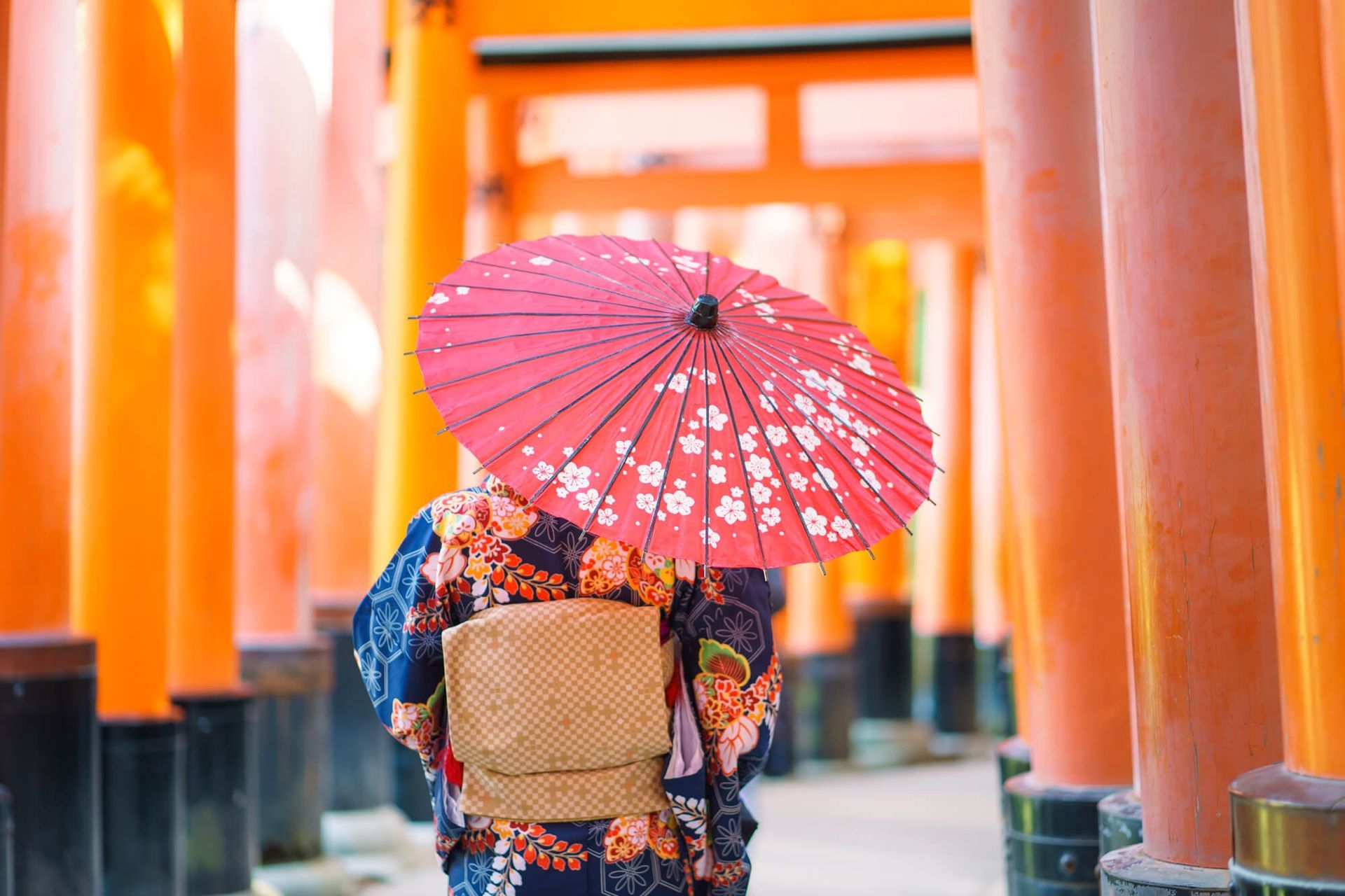 Una mujer con kimono sostiene un paraguas rojo.
