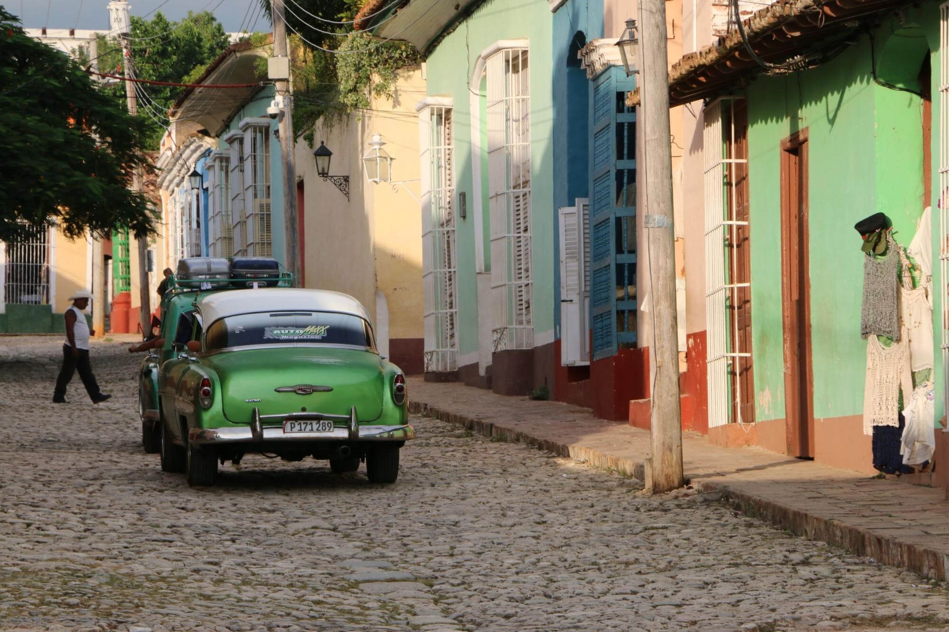 Un coche verde está aparcado en una calle adoquinada.