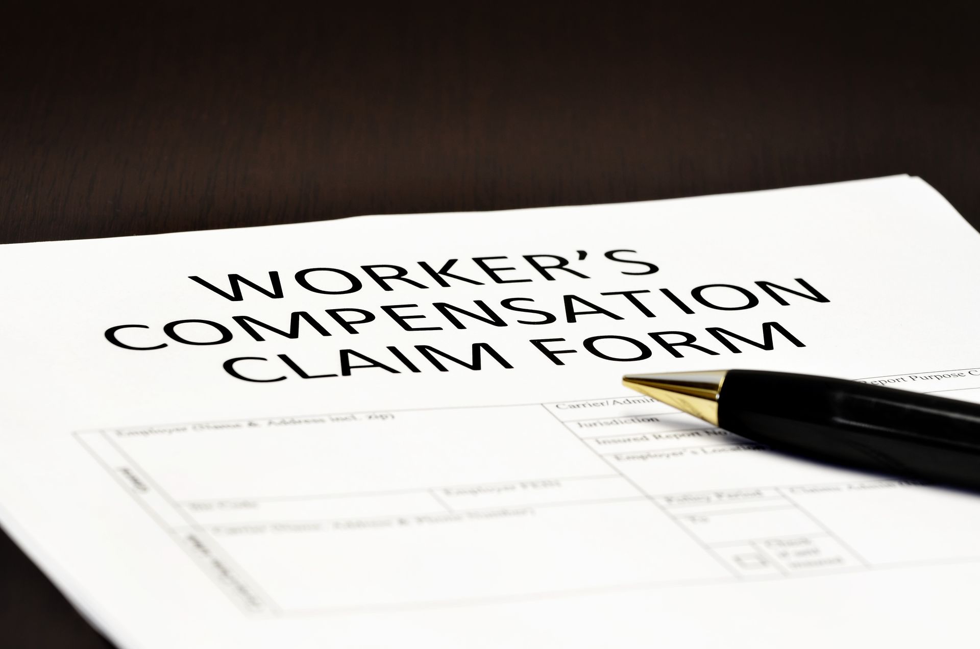 A pen is sitting on top of a worker 's compensation claim form.