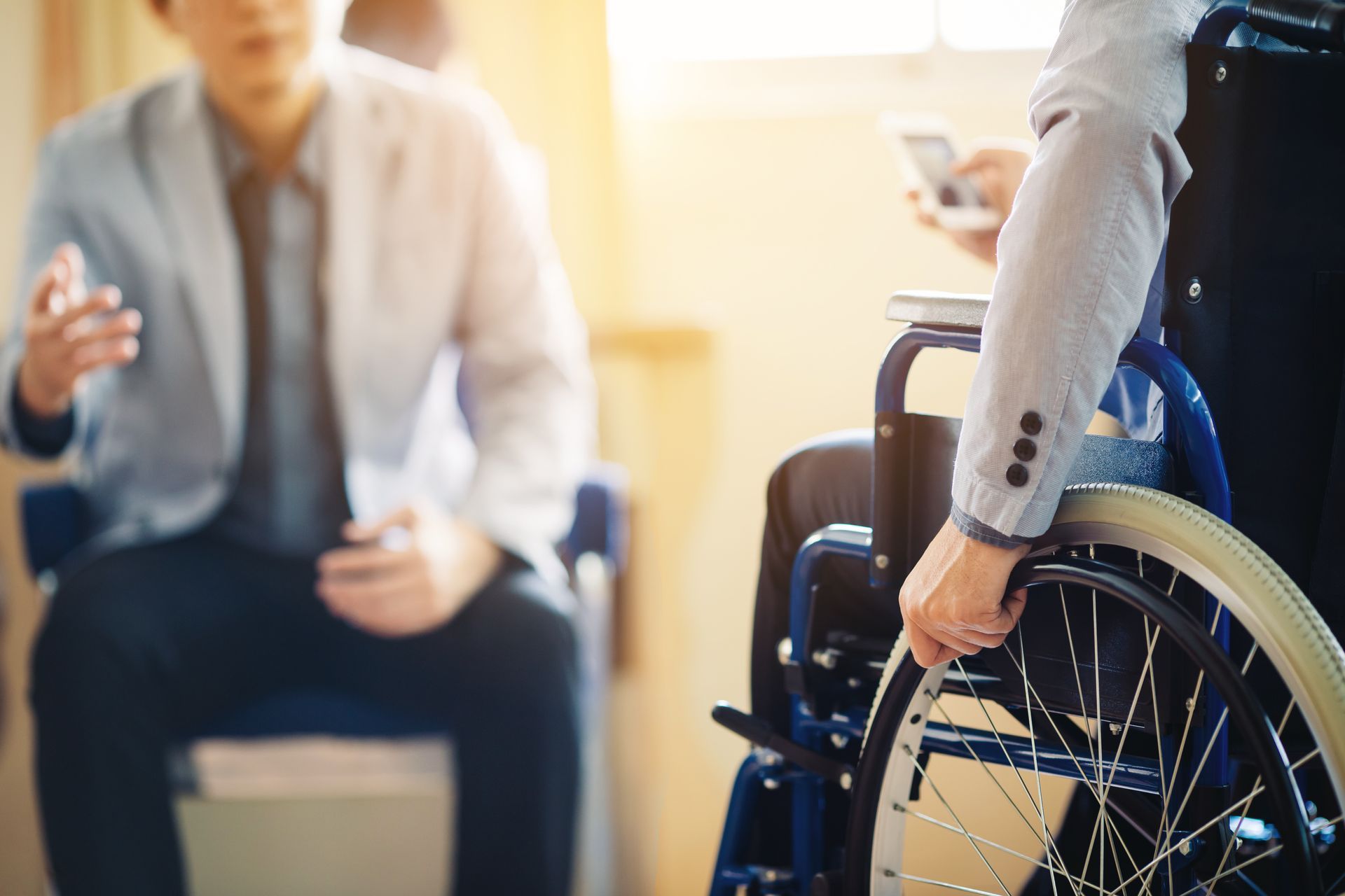 A man in a suit is sitting next to a woman in a wheelchair.