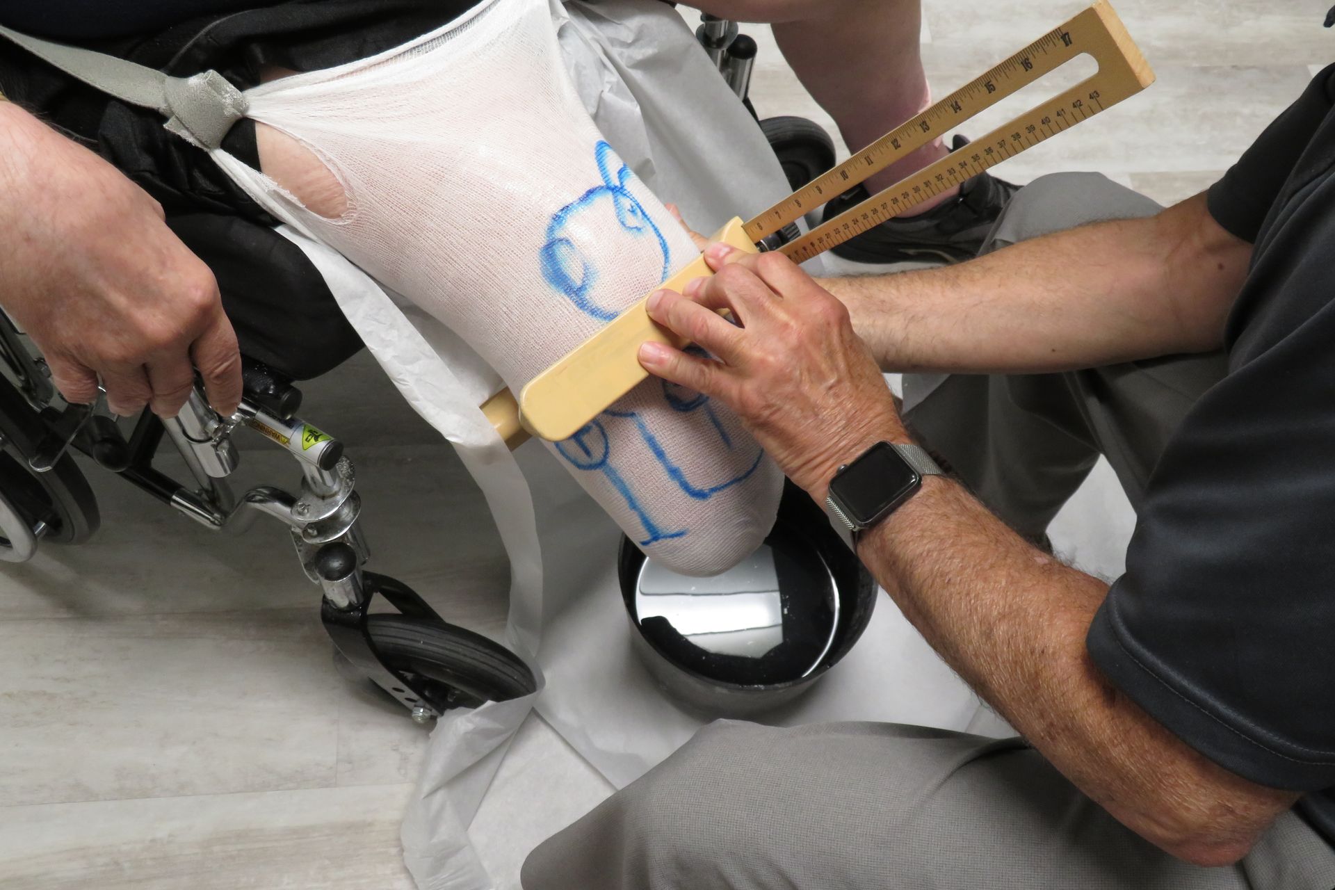 A man is measuring a person 's leg with a ruler.